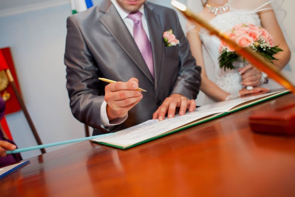 Couple signing a marriage certificate at a legal office desk