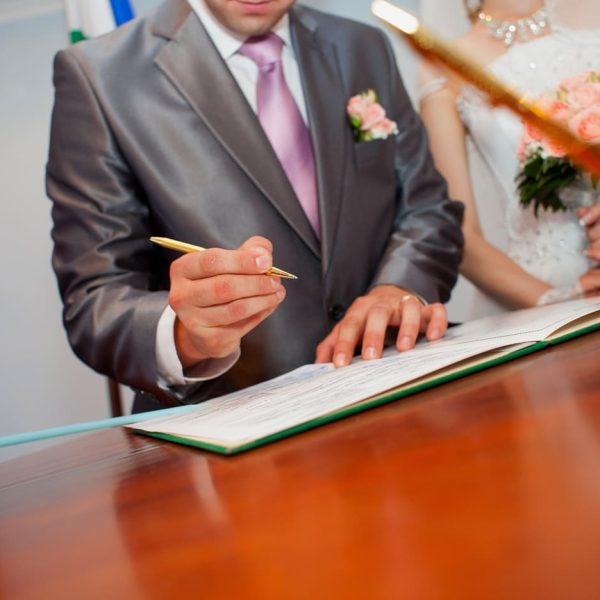 Couple signing a marriage certificate at a legal office desk