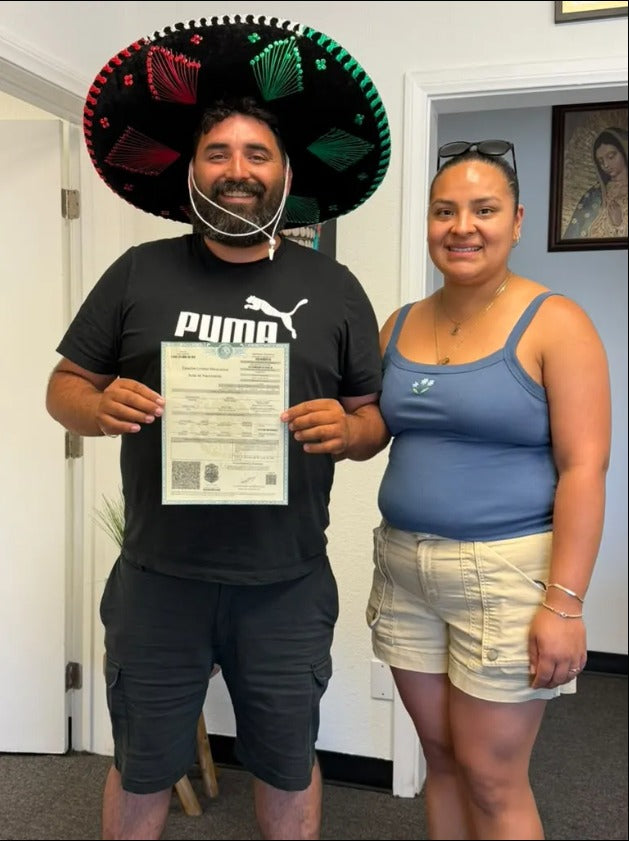Happy couple holding Mexican birth certificate after getting dual nationality with DNExpress for Independence Day 2026