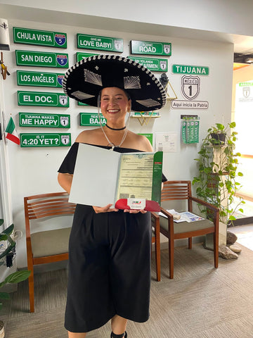 Clienta feliz de DNExpress sosteniendo su acta de nacimiento mexicana tras obtener la doble nacionalidad en oficina de Tijuana